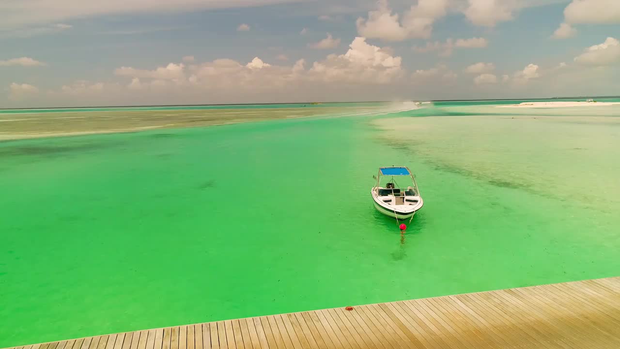 鸟瞰图，马尔代夫，在透明的海水中，快乐的女人穿着白色的衣服在海滩上的桥上。梦想旅行，奢华生活视频下载