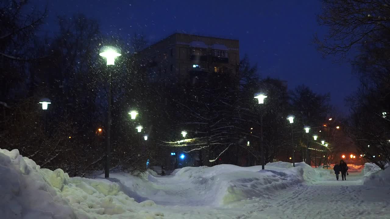 城市广场的夜巷被灯笼照亮了。正在下大雪。视频下载