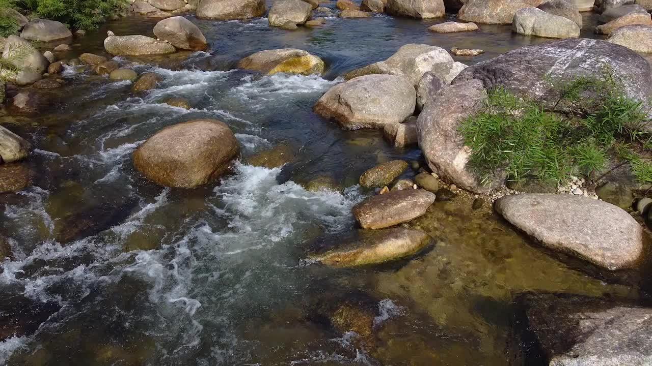 风景山涧瀑布流过岩石通过绿色植物在森林。视频素材