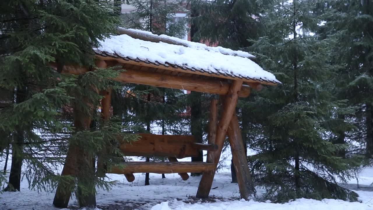 在冬天下雪的时候，公园里的空木秋千上有常青树视频素材