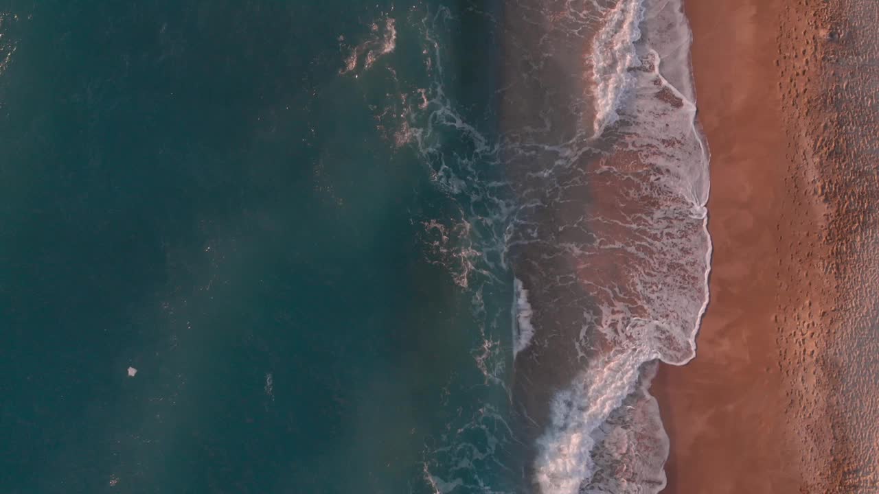 日落时巨大的海浪拍打着沙滩。热带沙滩与绿松石海浪，溅起白色泡沫。美丽的日落视频素材