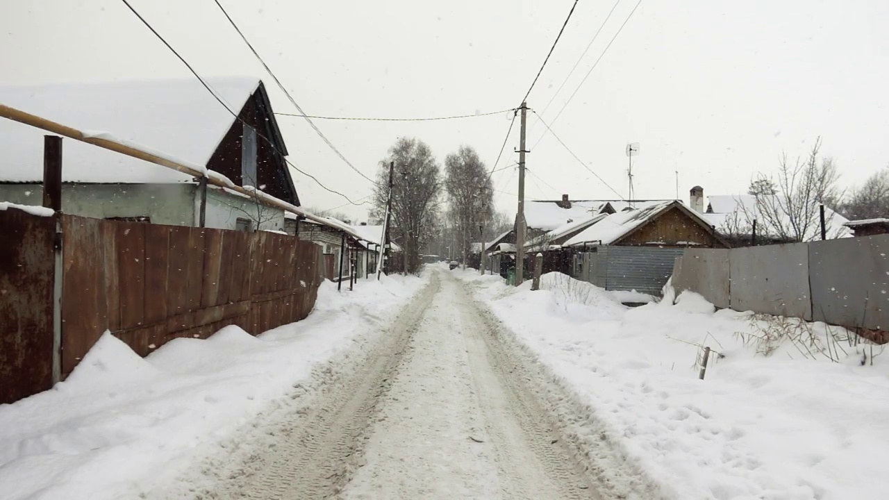 一个村庄的道路景观在一个冬天与雪花飘落在一个缓慢的动作视频素材