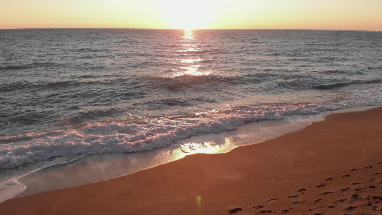 海面上的日落，海浪拍打着海滩，溅起白色的泡沫。美丽的日落。夏天的海景。自然美视频素材