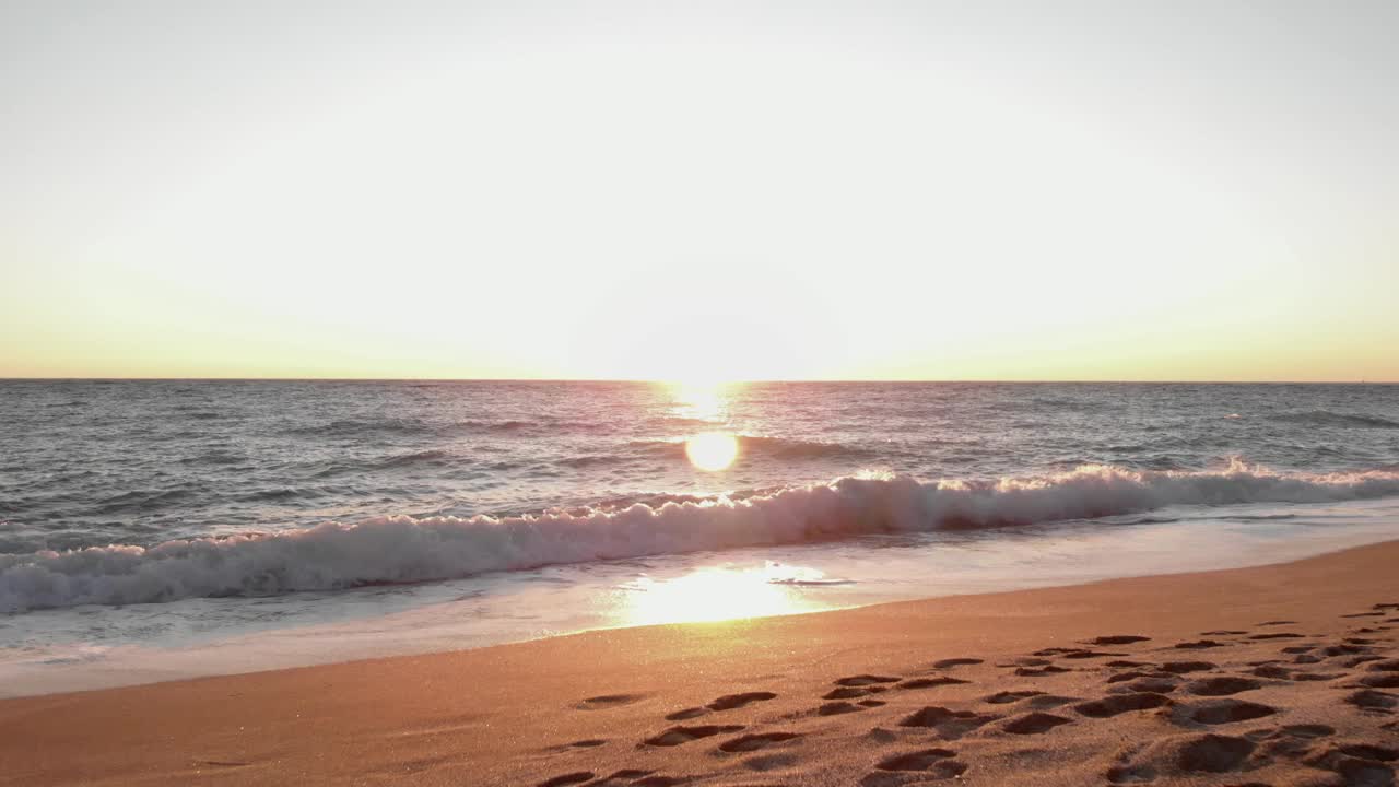 日落时，海浪拍打着海滩。海面上的夕阳。沙滩海上日落。太阳了地平线视频素材