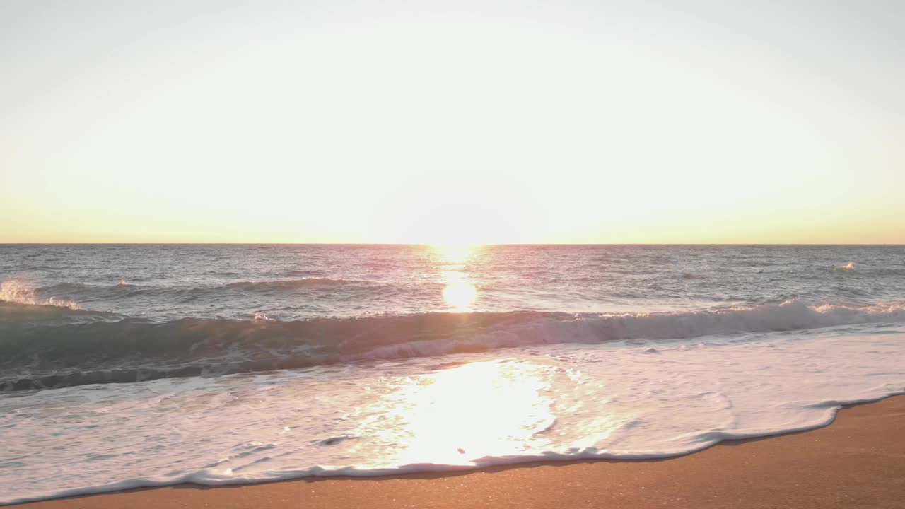 太阳触及海浪，美丽的日落。阳光反射在海水表面。海面上粉红色的日落视频素材