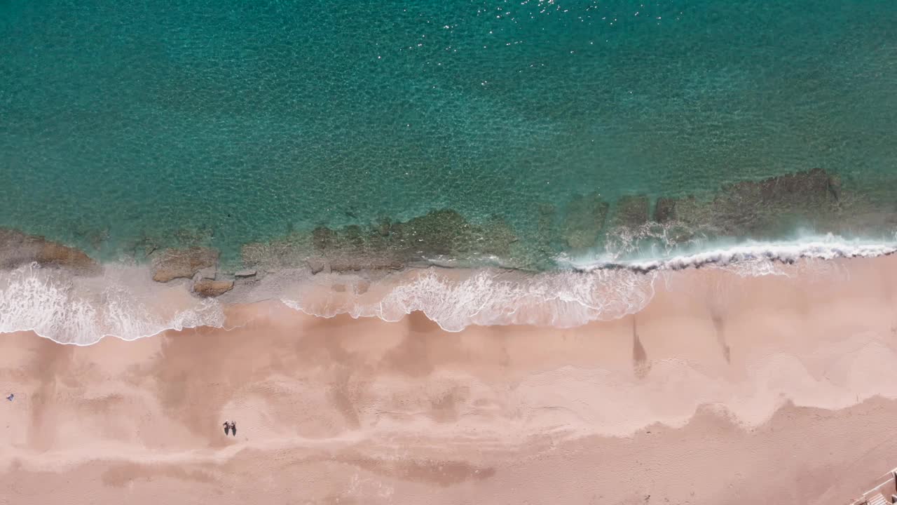 蓝色的海浪拍打着沙滩。海浪和美丽的热带沙滩，俯视图。海浪从上面拍打着空旷的沙滩视频素材