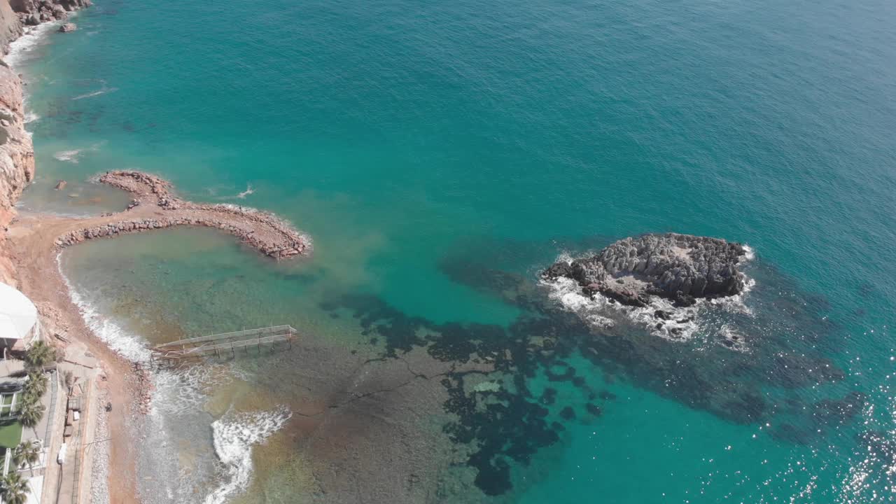 美丽的海景与岩石悬崖和海浪冲击岩石。蔚蓝的海水。平静的海浪拍打着岩石峭壁，溅起白色的泡沫视频素材