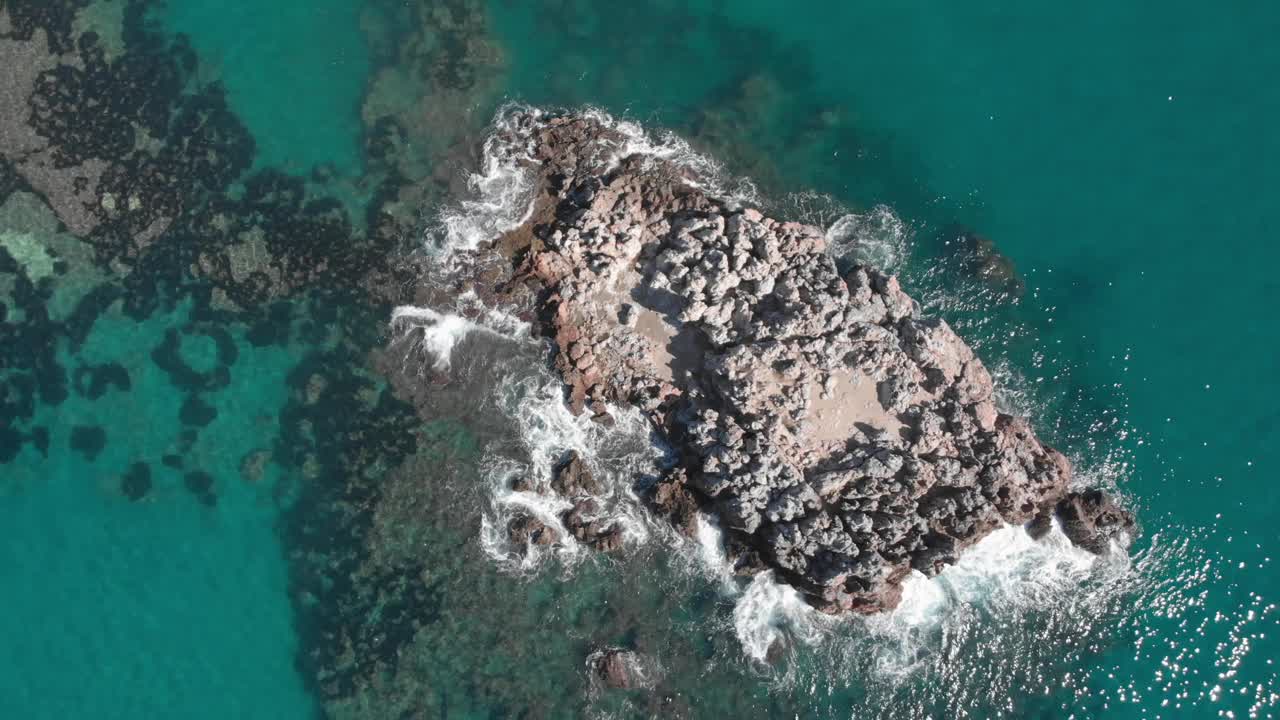 顶视图的空石岩石悬崖在蓝色的绿松石海。海浪拍打着岩石峭壁。美丽的海浪溅起白色的泡沫。从上面海景视频素材