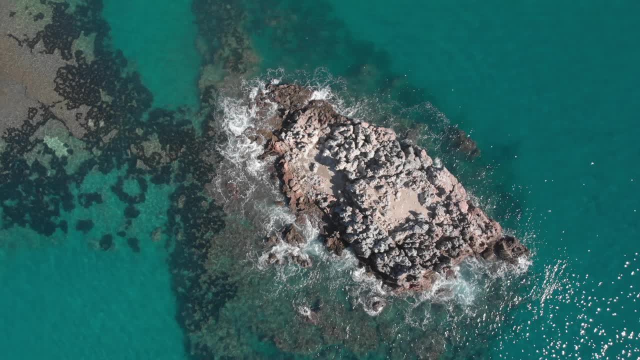 海浪翻滚的岩石悬崖。无人机飞越蓝色海洋，海岸有巨大的石阵。阳光明媚的夏日里，到处是岩石和海浪视频素材