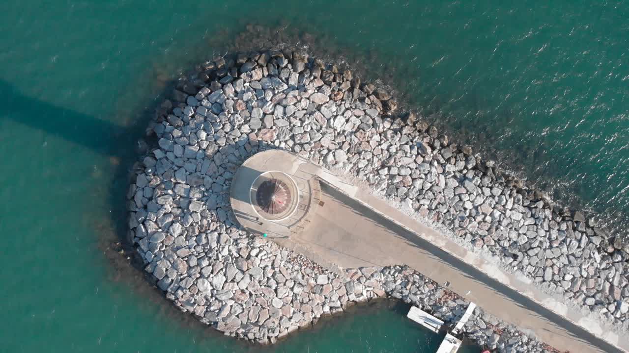 俯瞰蓝色泻湖上的白色灯塔。Alanya,土耳其。游客在码头的古老灯塔周围散步，无人机拍摄视频素材