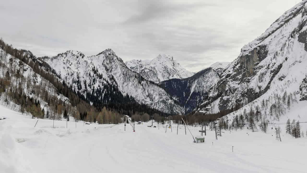 在一个多云的冬日里，欧洲阿尔卑斯山上白雪覆盖的山脉和废弃的滑雪场视频素材