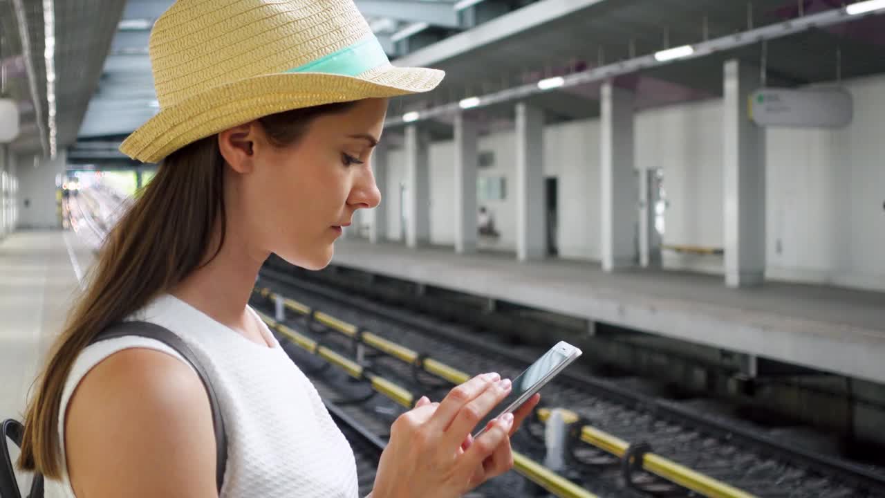 年轻女子在地下地铁站。女性游客在等火车时使用手机视频素材