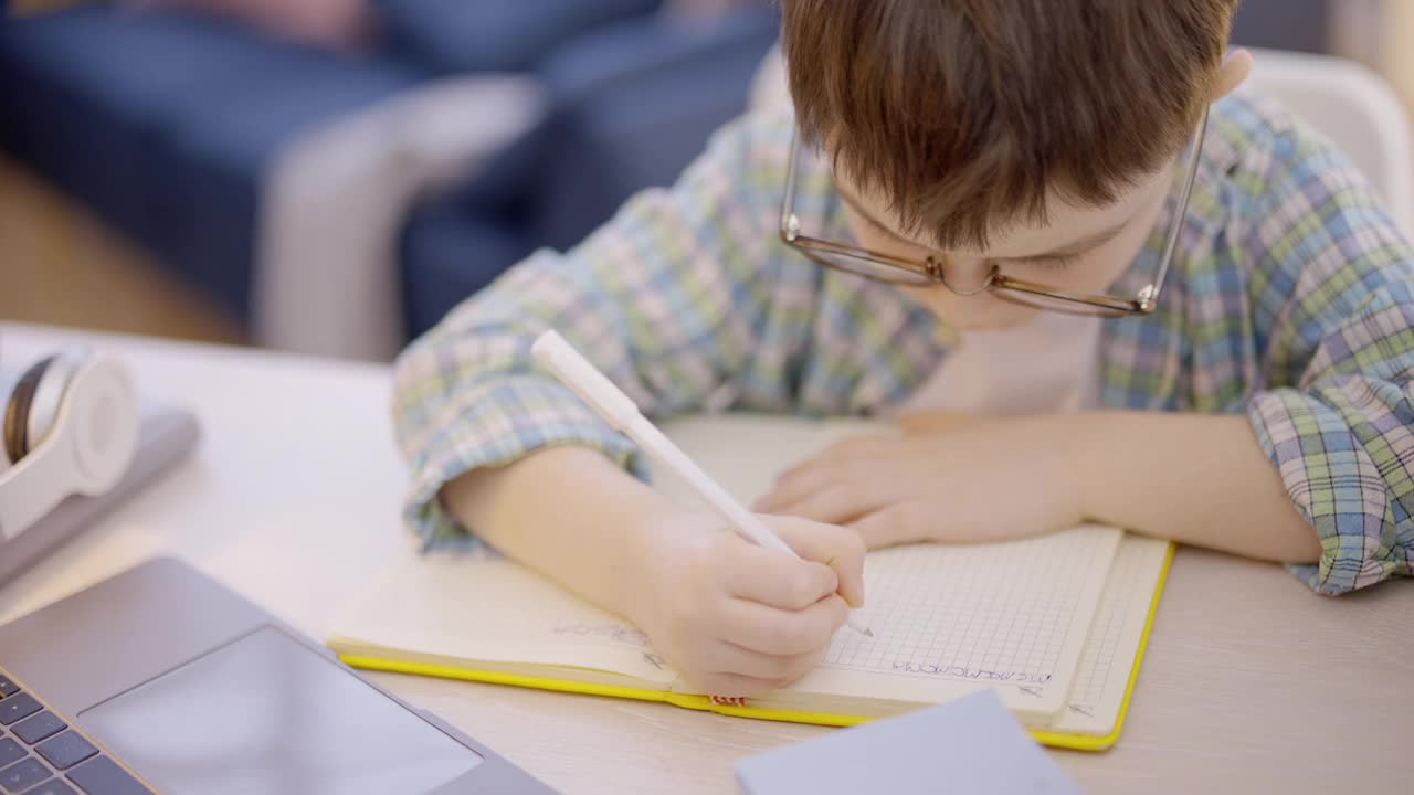 戴眼镜的孩子在做笔记本作业，小学视频素材