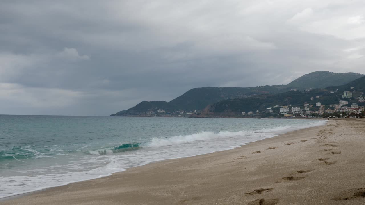 空旷的沙滩与海浪在黄昏日落。傍晚在海边。土耳其阿兰亚市海岸线。热带夏季海滩在雨天刮风的日子视频素材