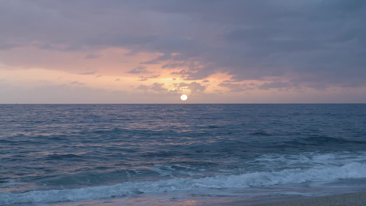 日落时美丽的海浪和多云的天空。夏日热带海滩日落海面。海浪冲击着沙子，产生白色的泡沫。迷人的海景。自然美视频素材