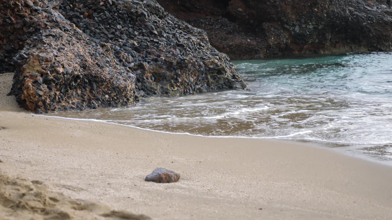 热带海滩与悬崖和绿松石水冲击沙子。美丽的海景。海浪拍打着岩石峭壁视频素材