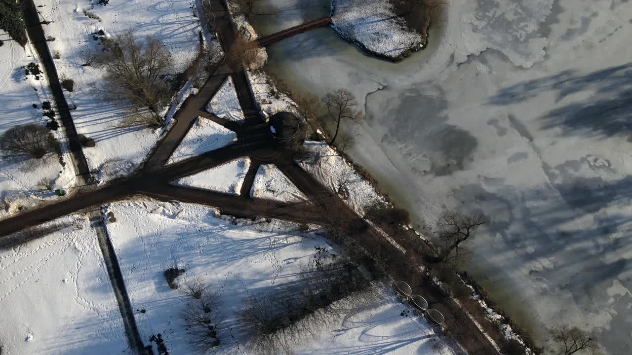 飞越冬季公园。摄像机是向下的。雪后的痕迹清晰可见。冰雪覆盖的湖。视频素材