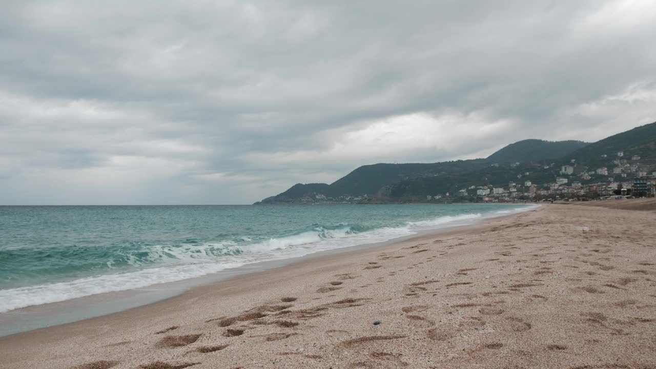 女人在沙滩上跑步沿着暴风雨的大海。女性在户外慢跑。跑步与运动的概念。美丽的海景视频素材