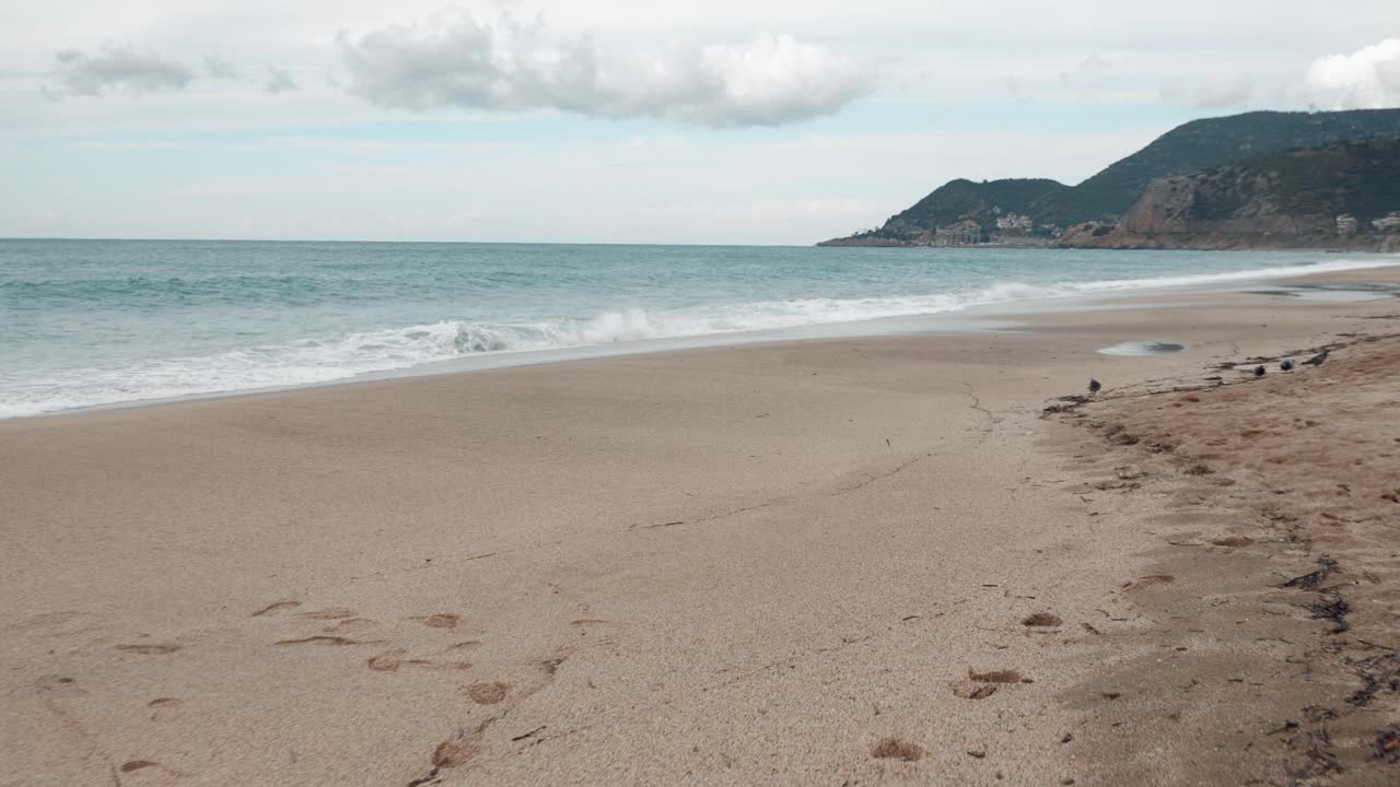 身着橘色夹克的年轻女子正在海滩上奔跑。快乐的女人在海边锻炼。雌鱼在海边慢跑。健身锻炼。海景对天空的风景。视频素材