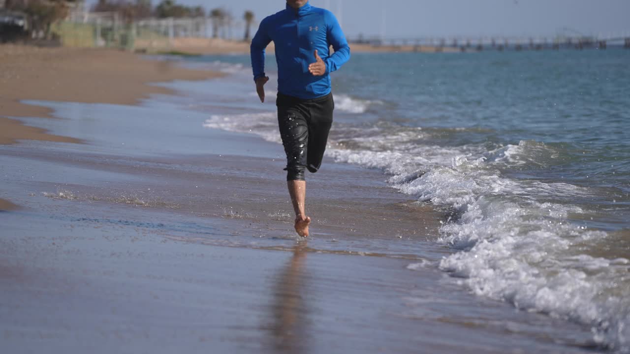 慢镜头男人在海滩上慢跑视频素材