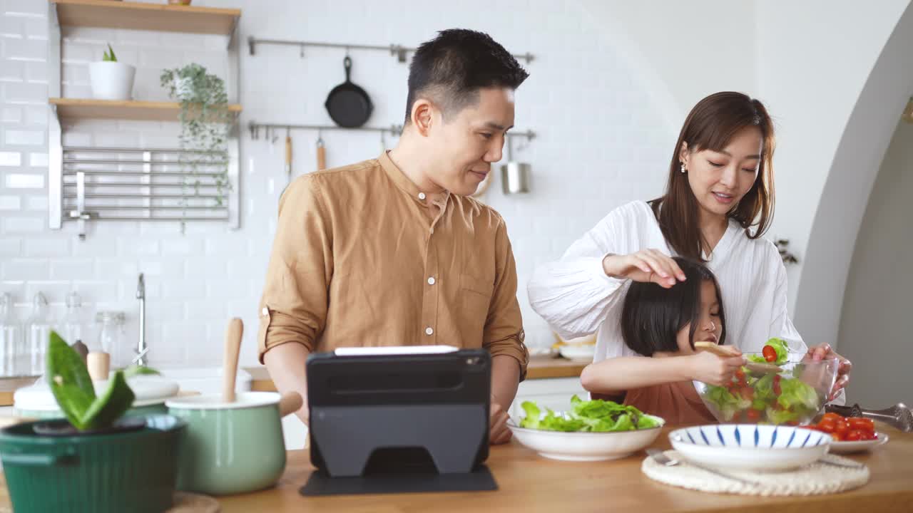 爸爸妈妈和女儿在家里的厨房里做沙拉视频素材