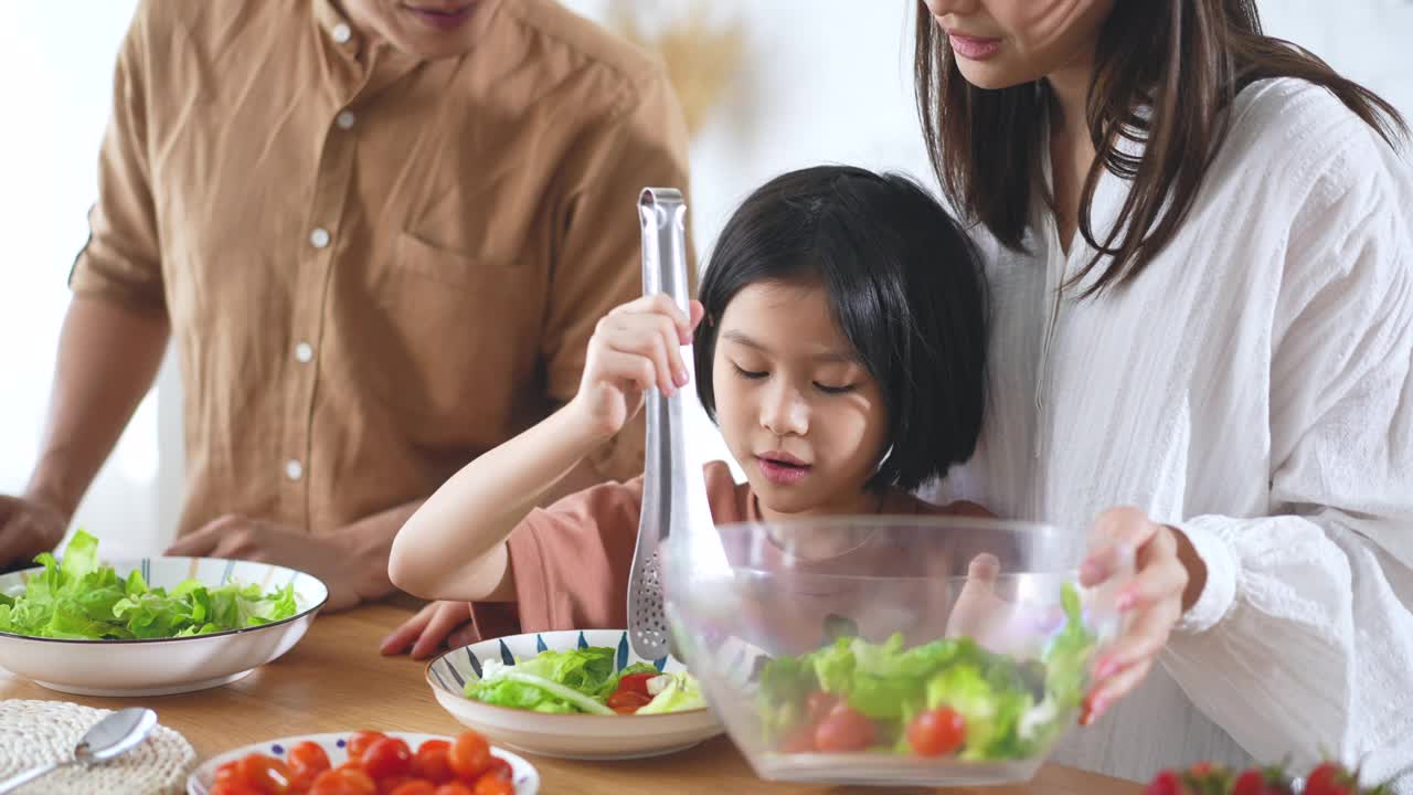 爸爸妈妈和女儿在家里的厨房里做沙拉视频素材