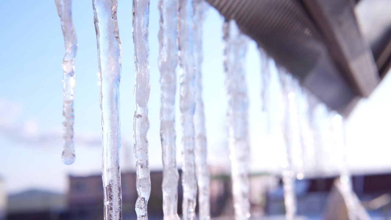 冰柱悬挂在冰雪上，背景是蓝色的天空。视频素材