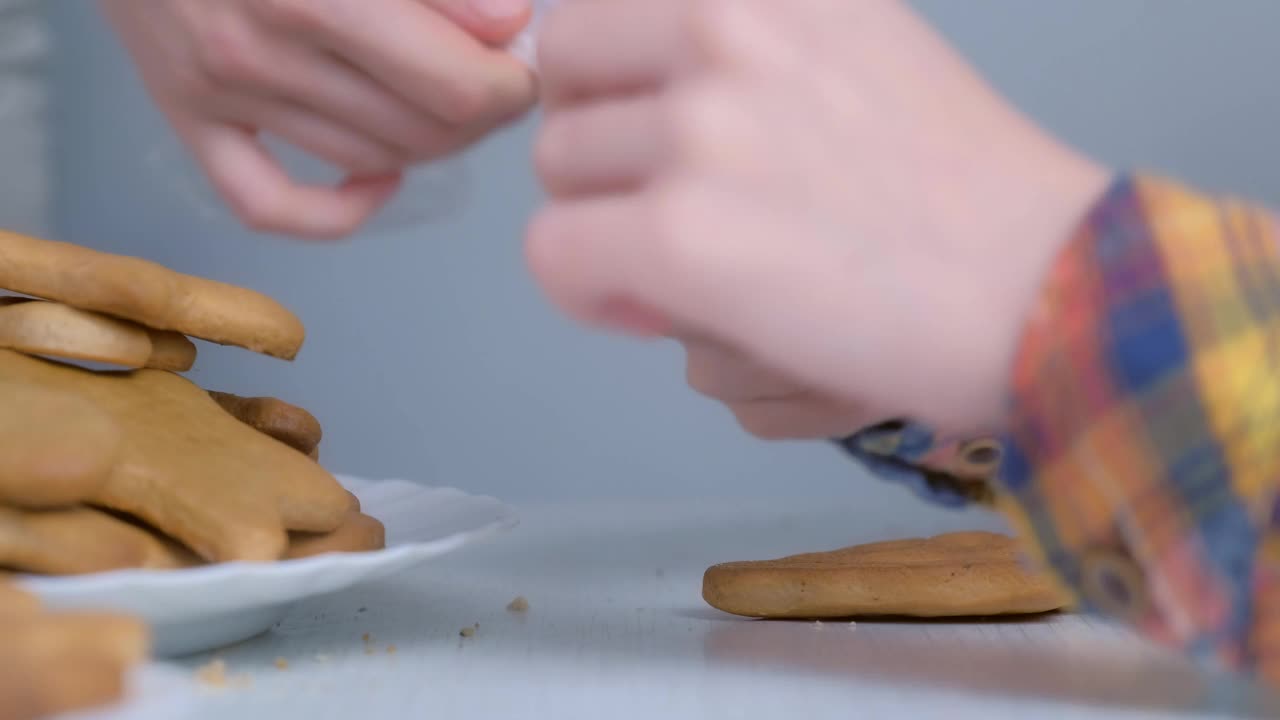 小男孩正在用糖霜装饰圣诞树形状的圣诞饼干。视频素材