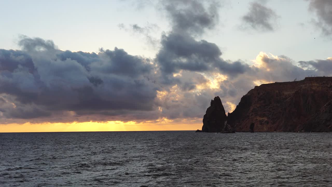 彩色温暖的日落在海上和火山玄武岩，就像在冰岛。海浪撞击着岩石，在温暖的夕阳照耀下溅起白色的泡沫。大自然永无止境的美丽视频素材