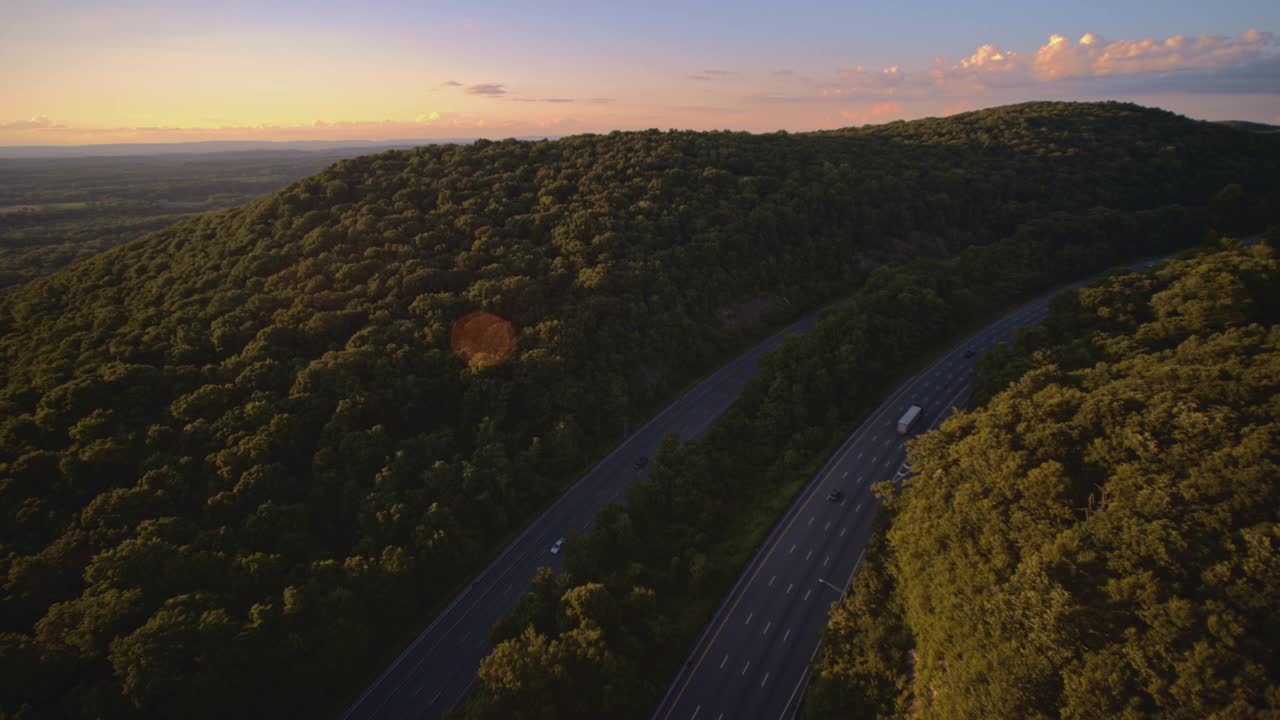 在新泽西州的I-80高速公路上的全景广角视图在日落，对着太阳，与一个强大的动态镜头光晕。航拍视频与平移摄像机运动。视频素材