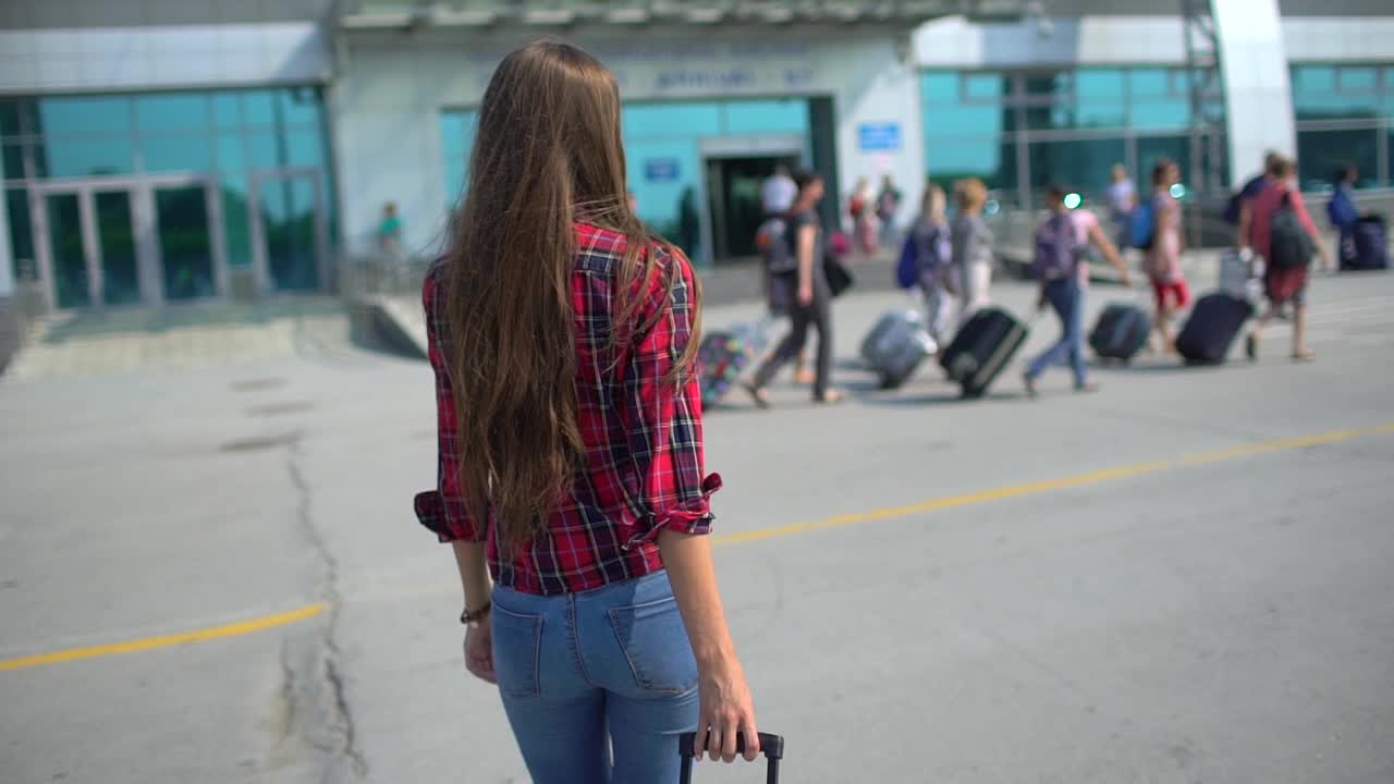 年轻女子正走向现代化的机场候机楼准备登机视频素材