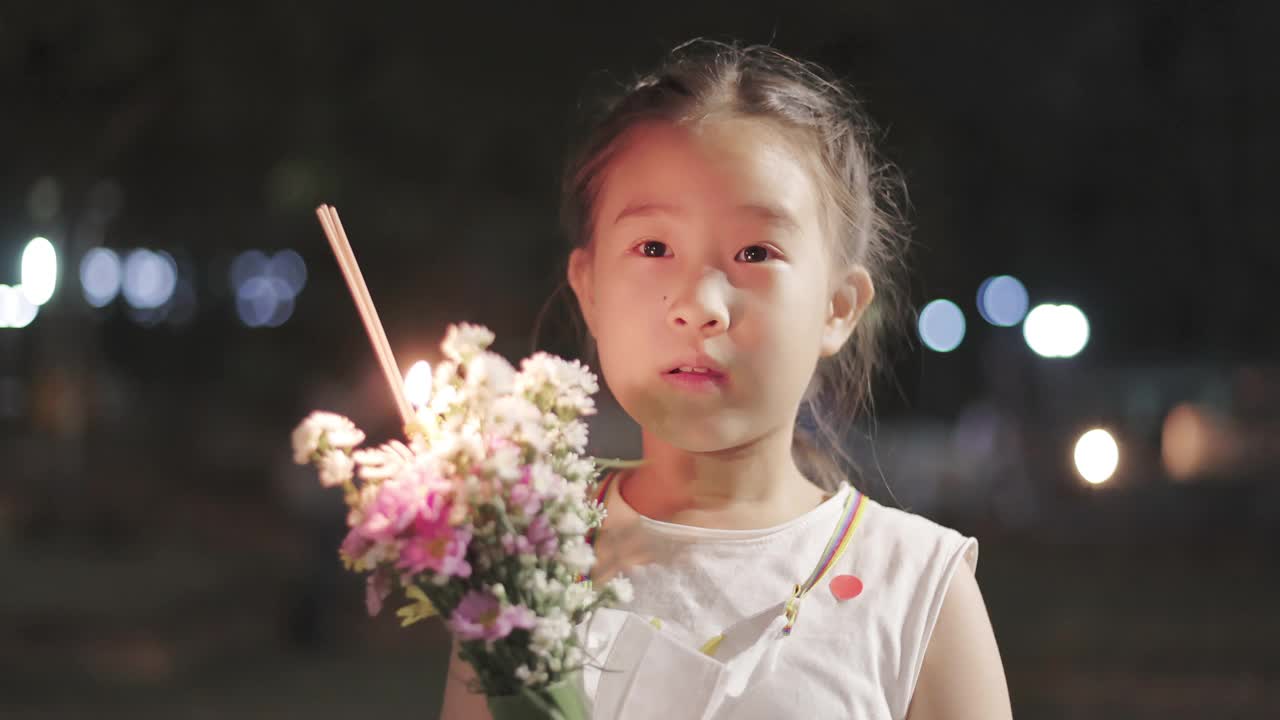 亚洲小女孩手里拿着花在夜里走在寺庙里视频素材