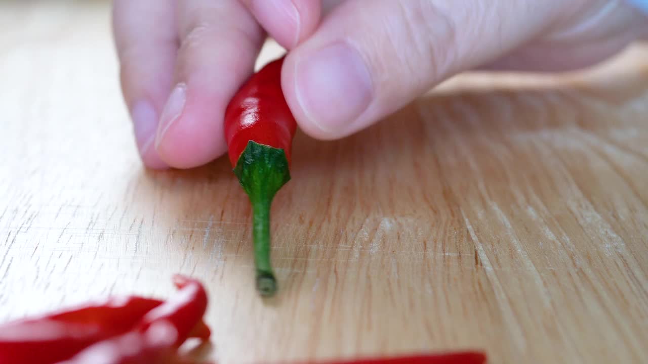 妇女在厨房的一块木板上切红辣椒，准备准备食物视频素材