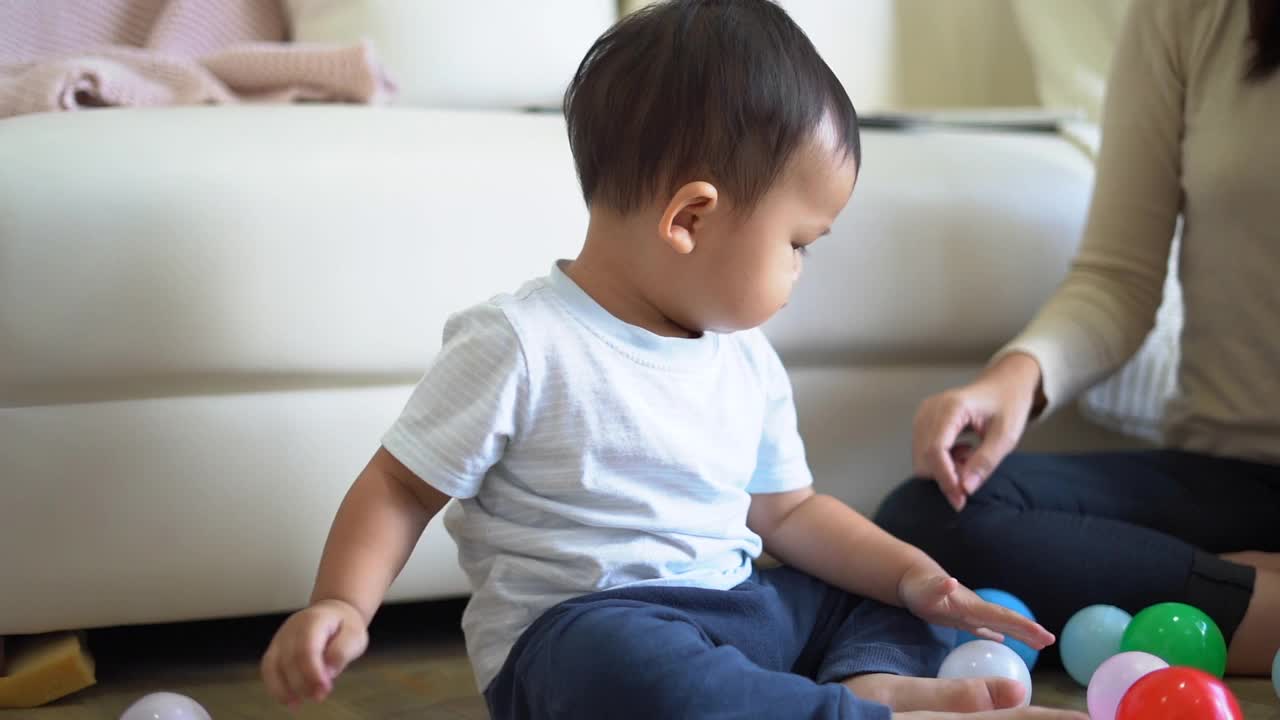 年轻的母亲和小男孩在家里沙发附近的地板上玩耍。幸福的家庭。视频素材