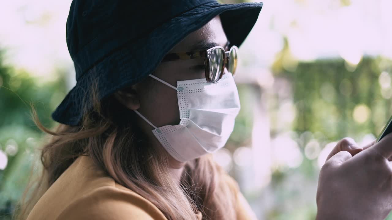 一个戴着口罩用手机的女人视频素材