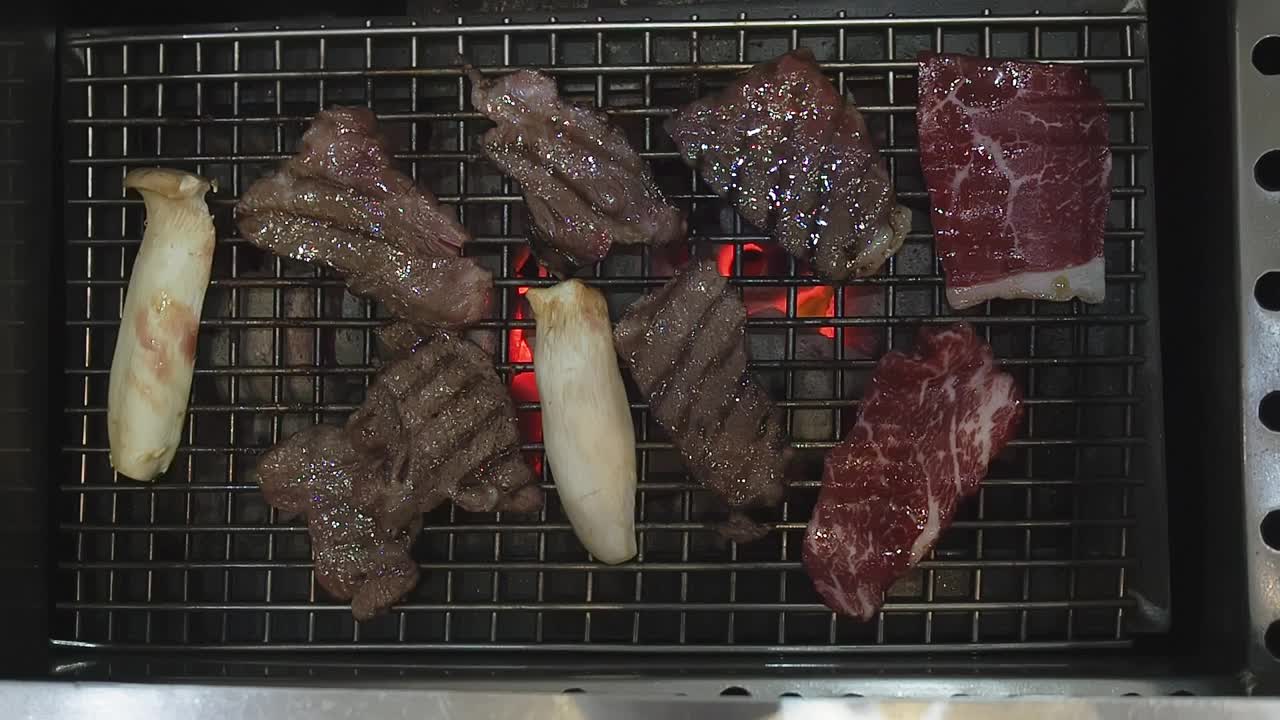 用钳子把肉放在烤架上。在烤架上烤肉。视频素材