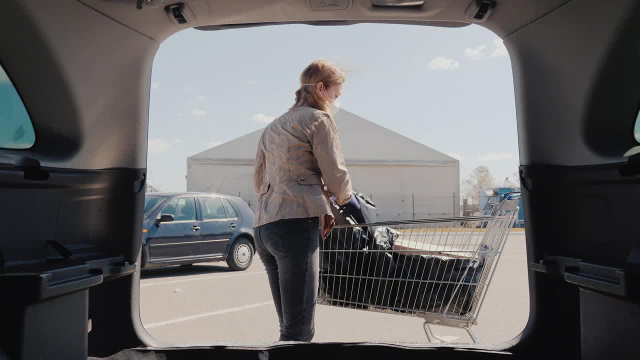 女人把装着从杂货店买的东西的袋子和几盒披萨放在汽车后备箱里视频素材