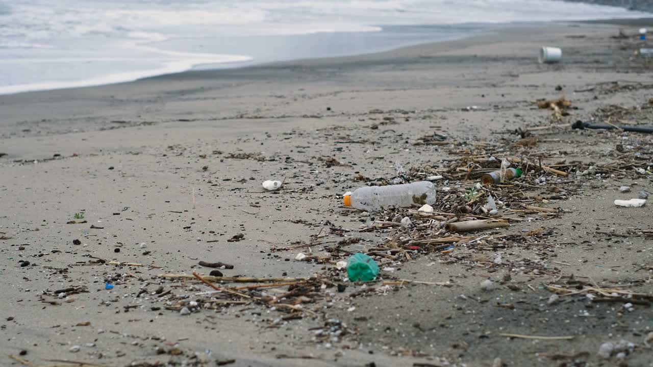 海洋海岸边的塑料瓶和容器垃圾，污染了海滩生态系统视频素材