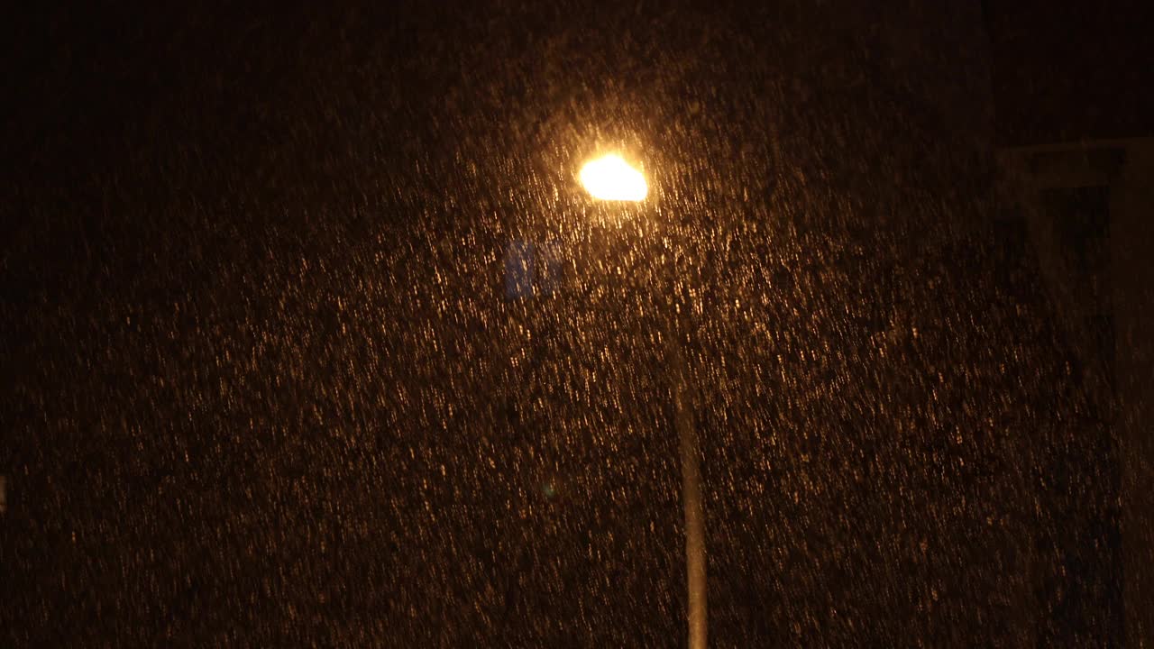 下雪的夜晚靠街灯照明。视频下载