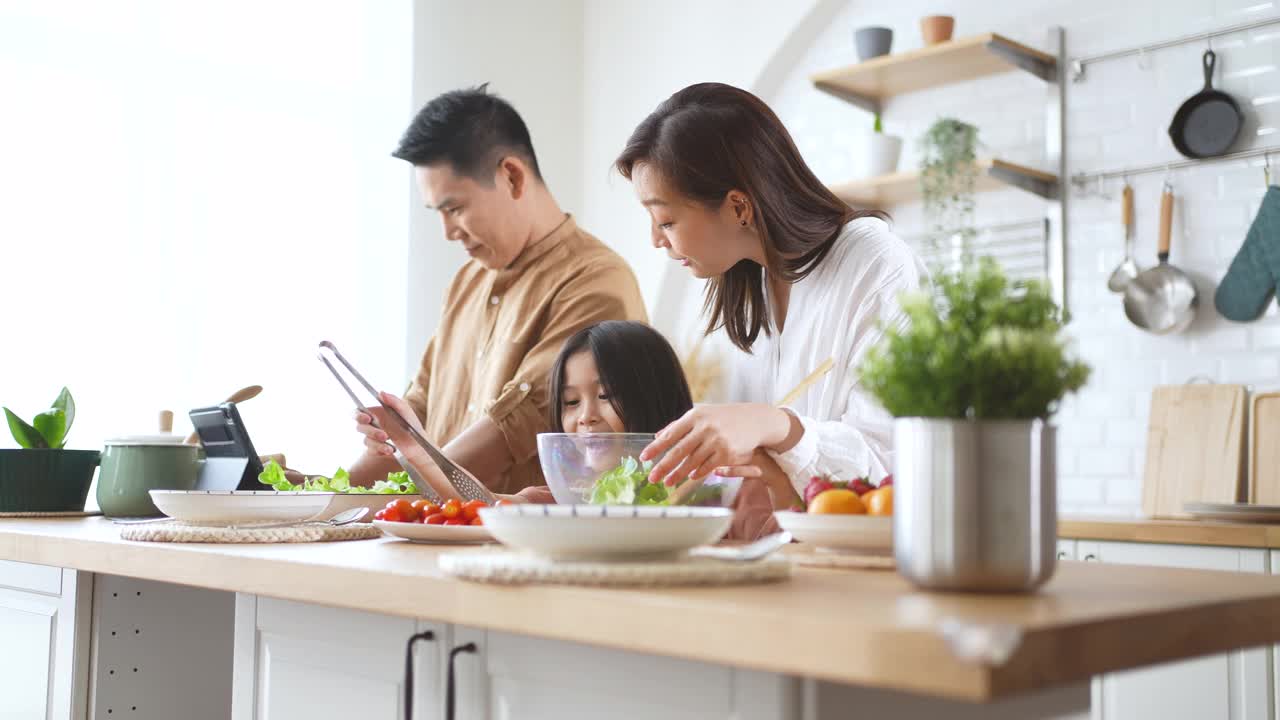 爸爸妈妈和女儿在家里的厨房里做沙拉视频素材