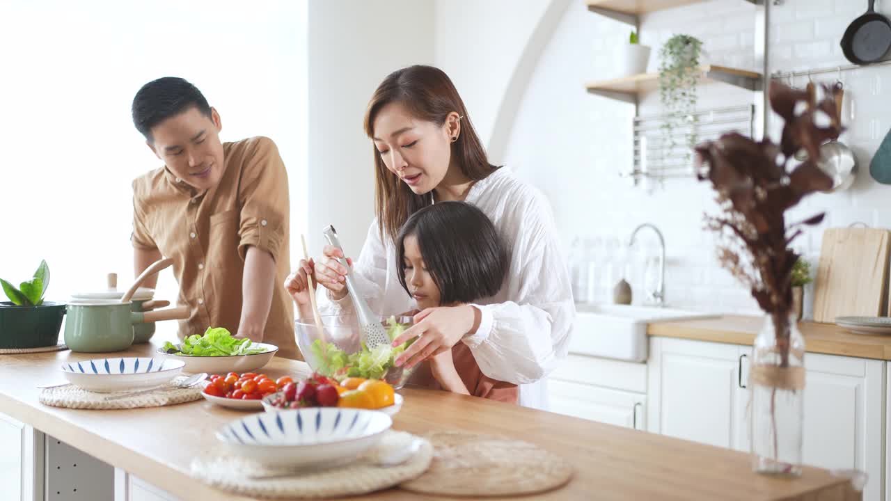 爸爸妈妈和女儿在家里的厨房里做沙拉视频素材