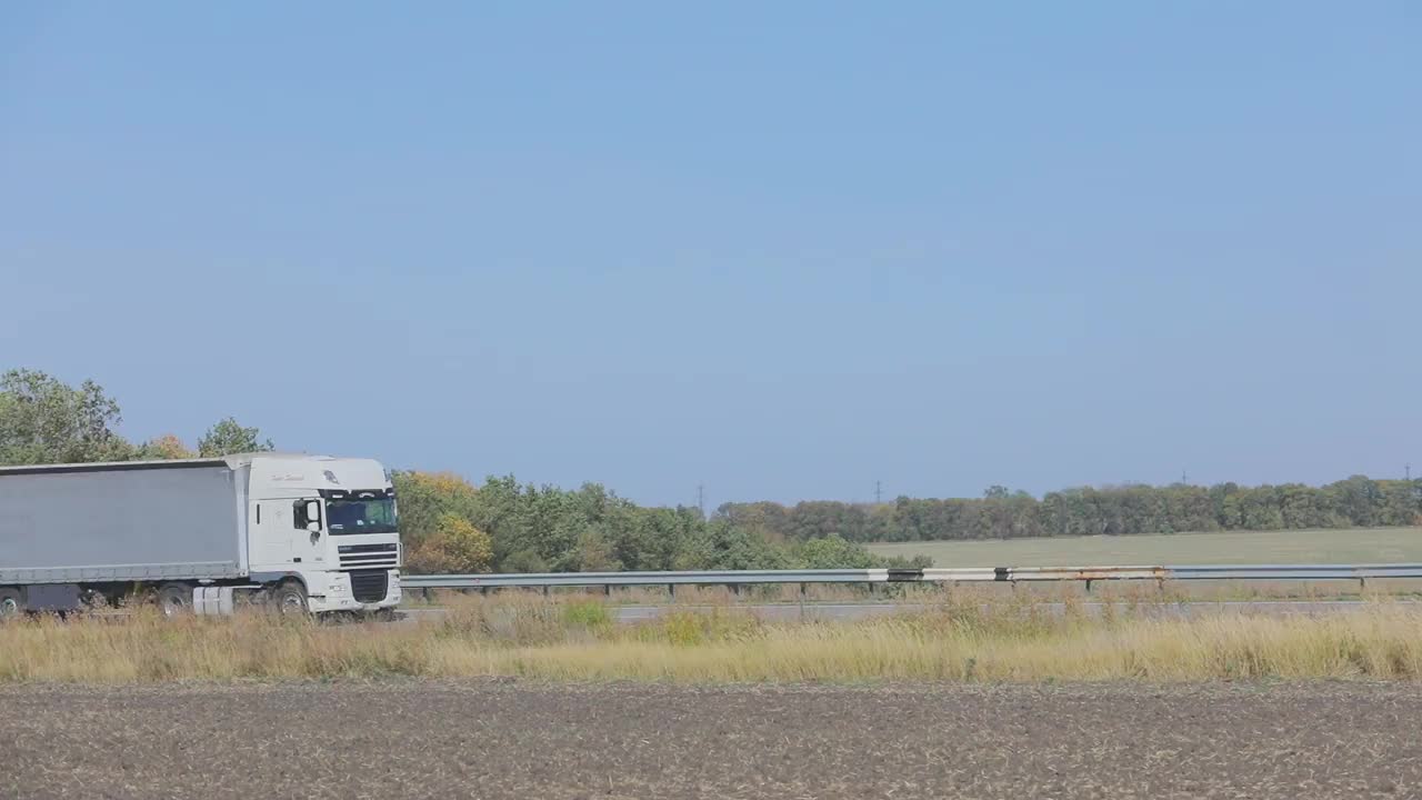 卡车在公路上行驶。卡车绕着田野和树林在公路上行驶视频素材