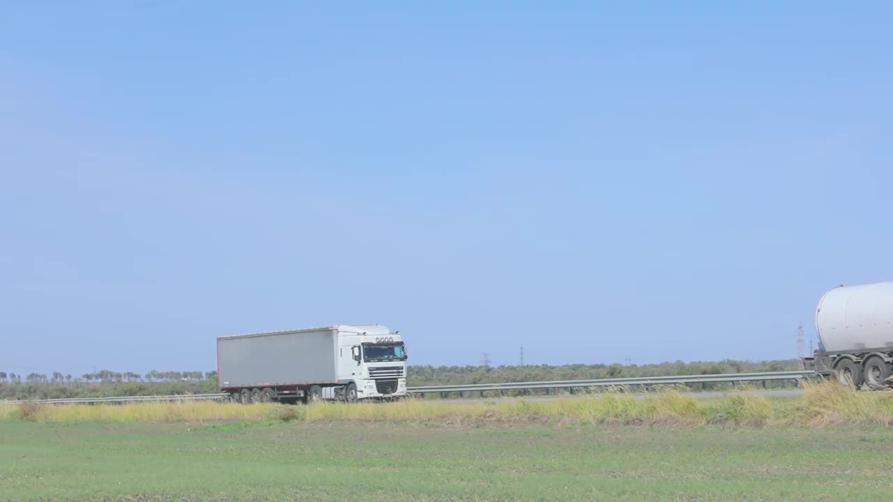 一辆白色的马车在阳光明媚的天气里沿着公路行驶。高速公路上的卡车视频素材