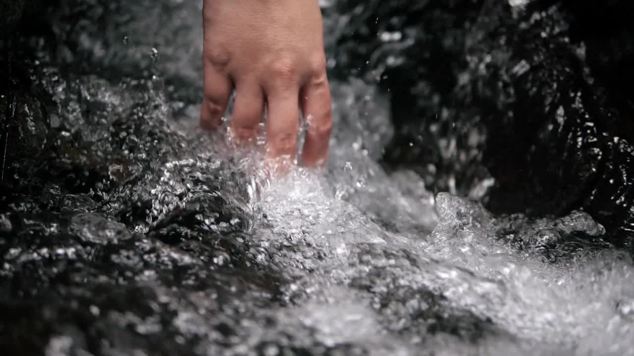 手触摸干净的水飞溅的溪流自然瀑布视频素材