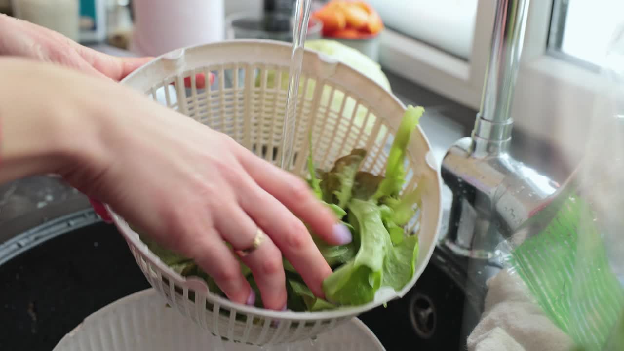 女人用手洗生菜叶。视频素材