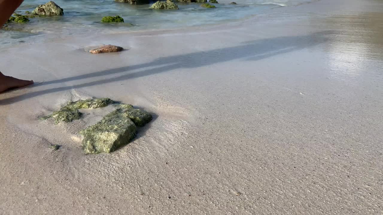 当加勒比海的海浪拍打着裸露的岩石时，雄性壮举在潮湿的沙滩上泼水。视频素材