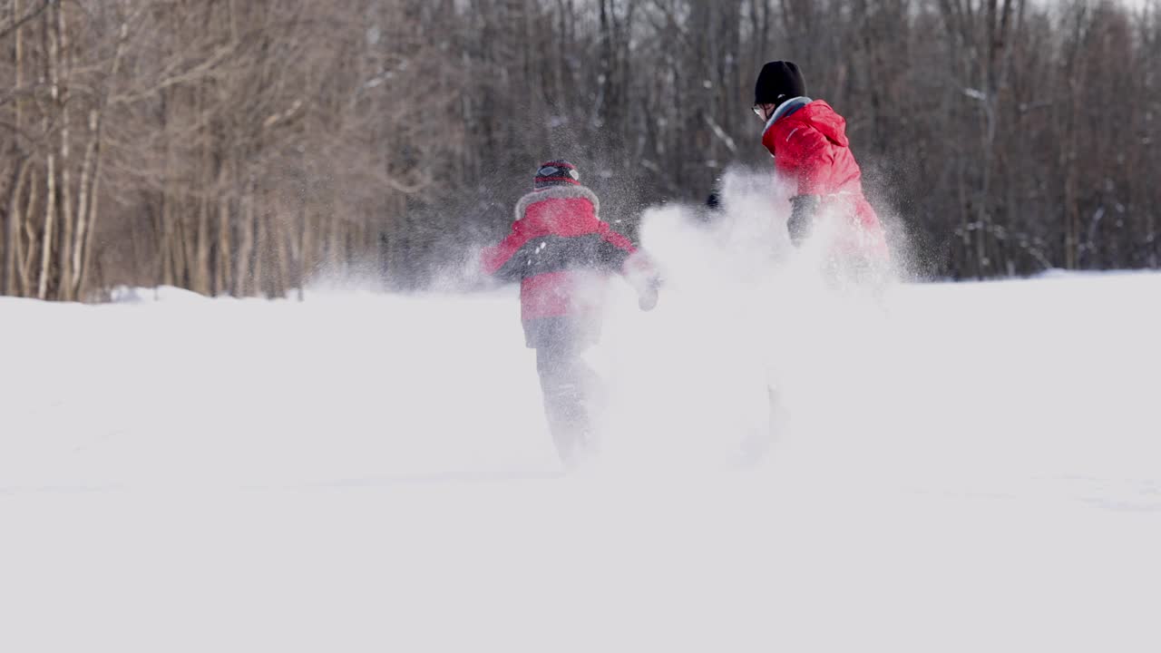 母亲和儿子跑与雪鞋在粉雪户外在冬天视频素材