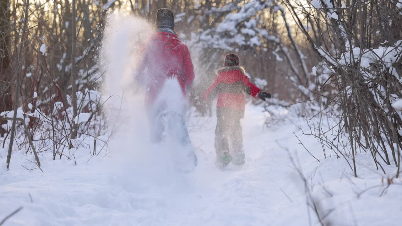 母亲和儿子跑与雪鞋在粉雪户外在冬天视频素材