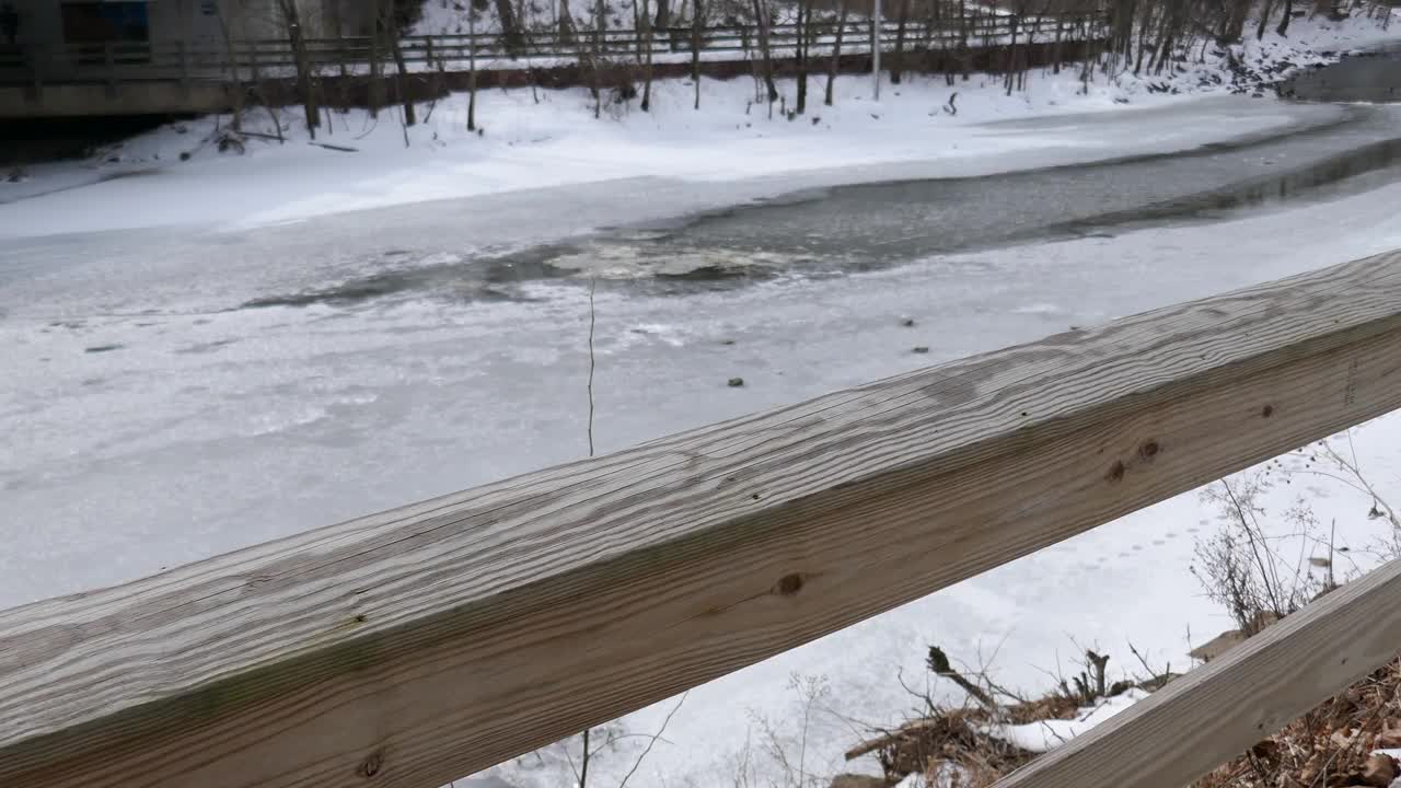 公园里结冰的小溪旁的积雪的木制人行道视频素材