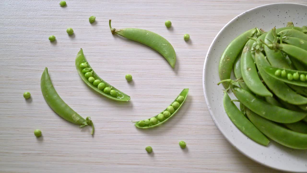 新鲜的绿豌豆放在白盘子里视频素材